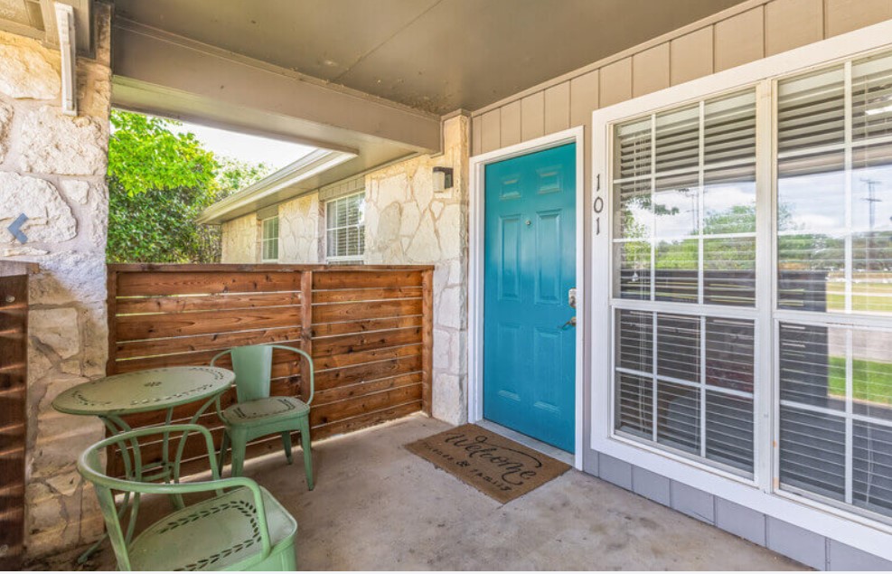a patio with a blue door and chairs at The Ten19 Apartments